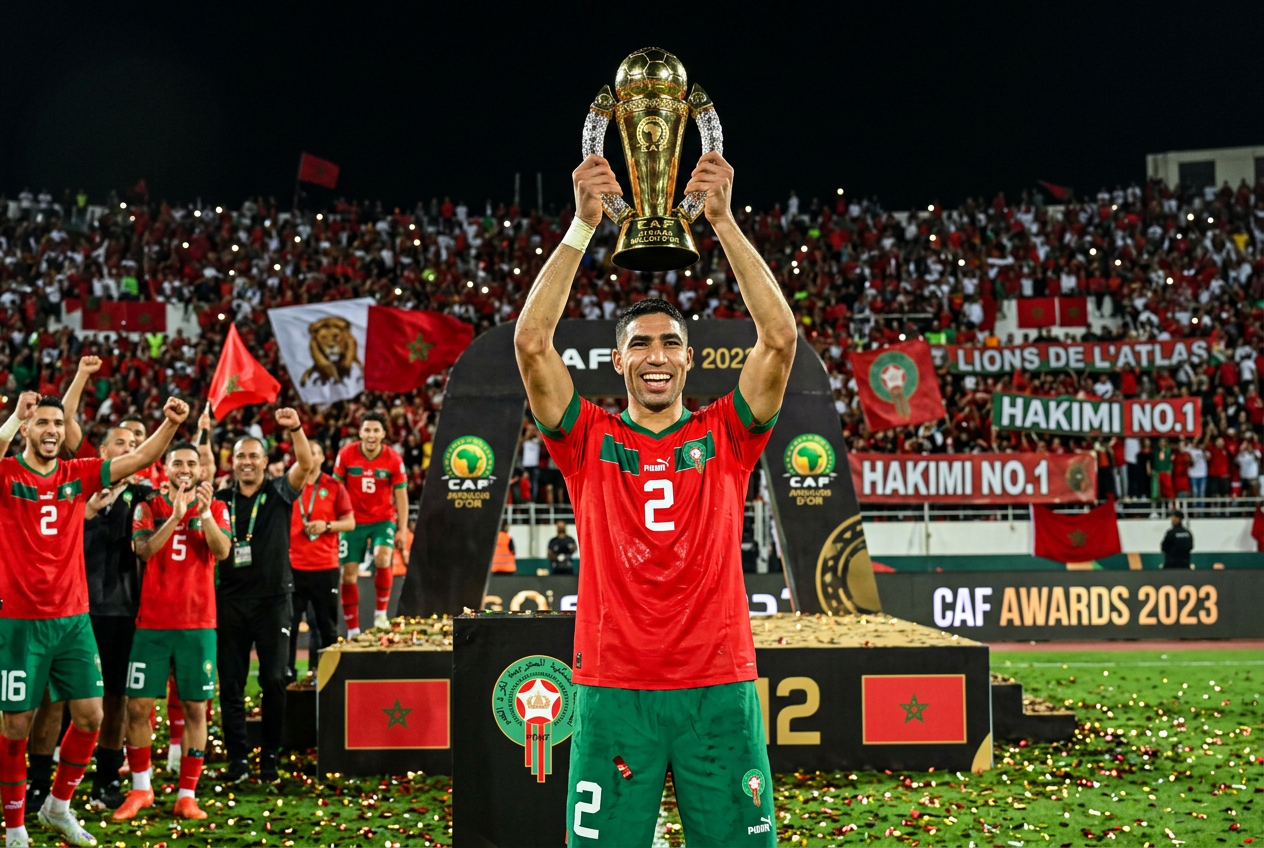 Achraf Hakimi soulève le trophée du Ballon d'Or africain en tenue rouge et verte
